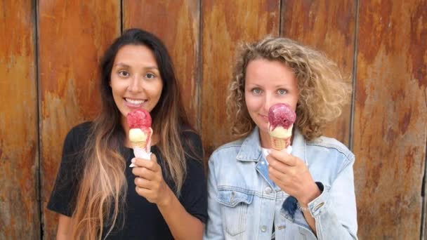 Девушки смотрят в камеру с мороженым в руках — стоковое видео