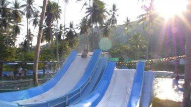 Çocuk yüzme havuzunda su kaydırağından kayarken eğleniyor. Yavaş Hareket.