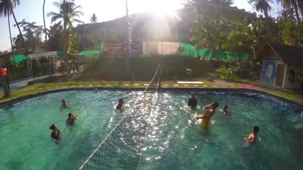 Gruppe von Menschen, die im Pool bei Sonnenuntergang Volleyball spielen. Zeitlupe. — Stockvideo