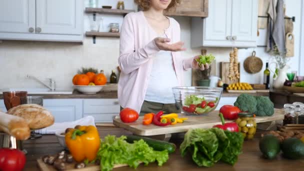 Femme enceinte cuisine salade fraîche de légumes biologiques sur la cuisine . — Video