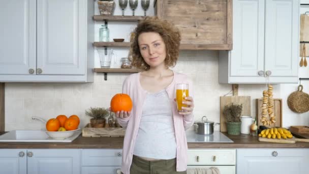 Zwangere vrouw met glas sinaasappelsap in de keuken — Stockvideo