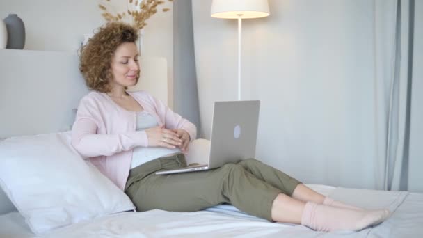 Έγκυος γυναίκα που χρησιμοποιεί φορητό υπολογιστή ξαπλωμένος στο κρεβάτι στο σπίτι — Αρχείο Βίντεο