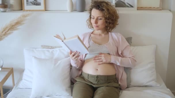 Glad graviditetskoncept. Ung gravid kvinna vilar hemma på sängen. — Stockvideo