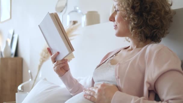 Glad gravid kvinna Vila och läsa en bok hemma — Stockvideo