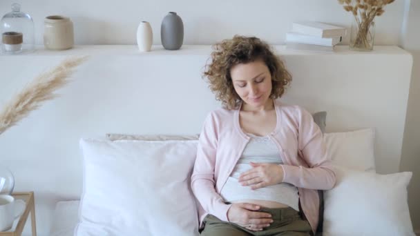 Feliz joven embarazada tocando su vientre con amor y cuidado esperando a su bebé . — Vídeos de Stock