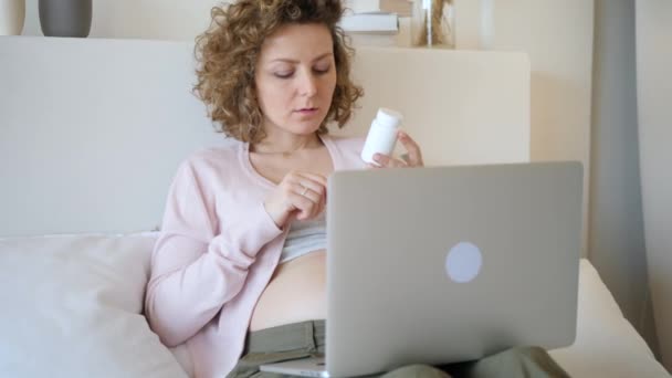 Zwangere vrouw controleren van de geneeskunde met behulp van laptop computer. Vitaminen en voeding tijdens de zwangerschap. — Stockvideo