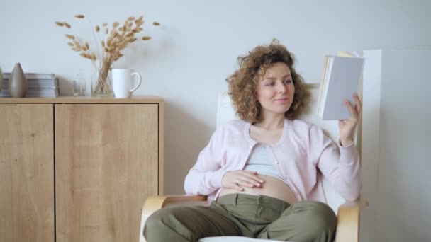 Έγκυος κορίτσι διαβάζει ένα βιβλίο στο σπίτι — Αρχείο Βίντεο