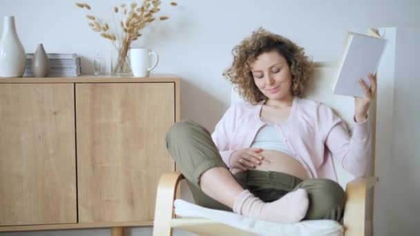 Grossesse, personnes, loisirs et mode de vie heureux Concept. Femme enceinte lecture à la maison . — Video