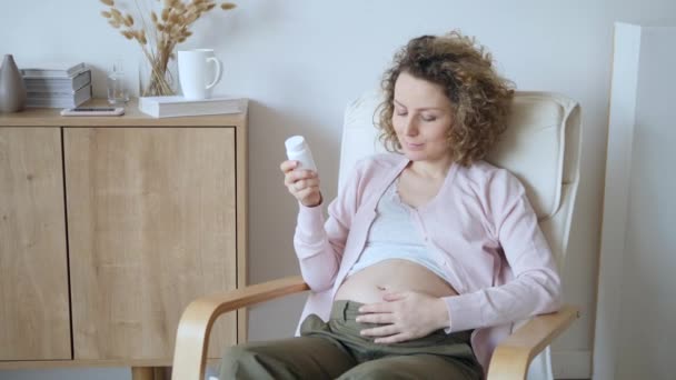 Zwangerschap, Geneeskunde, Farmaceutica, Gezondheidszorg en Mensen Concept - Zwangere vrouw met medicijnen pot lezen Label. — Stockvideo