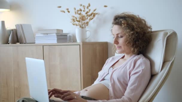 Giovane donna incinta che utilizza il computer portatile a casa . — Video Stock