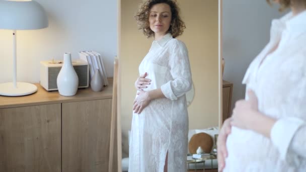 Jeune femme enceinte regardant au miroir à la maison — Video