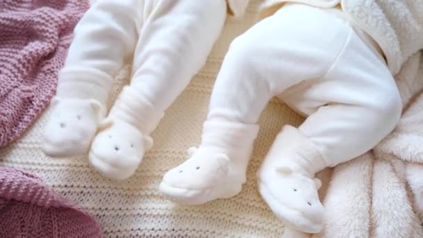 Pieds de bébé dans des chaussures douces en peluche reposant sur une couverture tricotée confortable. Gros plan . — Video