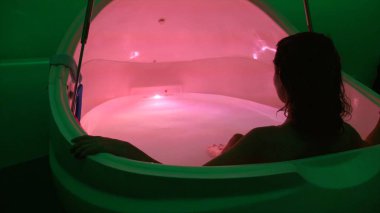 Woman Relaxing In Isolation Tank Or Sensory Deprivation Tank In Floating Center clipart
