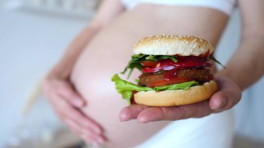 Sağlıksız yiyeceğe sağlıklı alternatifler. Hamile Kadın Vegan Burger Tutuyor.