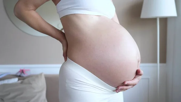 임신 한 여성은 요통을 앓는다. 벨트를 매는 일. — 스톡 사진