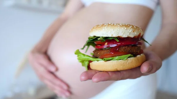 Здоровые альтернативы нездоровой пище. Беременная женщина держит веганский бургер . — стоковое фото