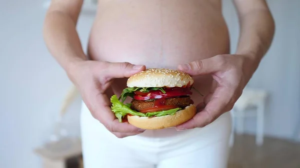 Terhes nő, kezében vegán burgerrel. Egészséges alternatívája a szemét élelmiszer. — Stock Fotó