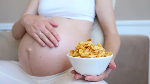 Dieta během těhotenství koncepce. Těhotná žena jíst francouzské hranolky. — Stock fotografie