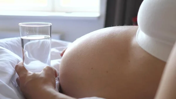 Těhotná žena drží sklenici vody. — Stock fotografie