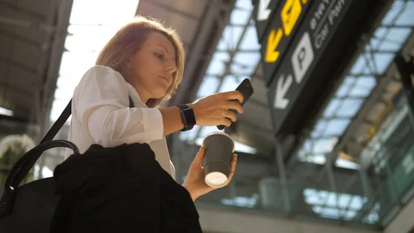 Passageiro viajante mulher de negócios vestindo Smartwatch no aeroporto usando Smartphone — Fotografia de Stock