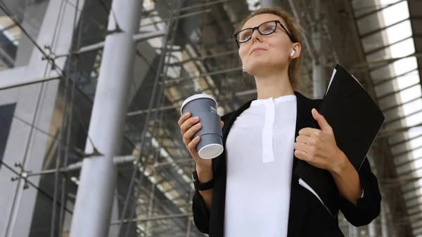 Stylish Business Woman With Coffee Wearing Bluetooth Earphones