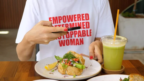 Современная стильная женщина фотографирует здоровую пищу со смартфоном в бистро . — стоковое фото