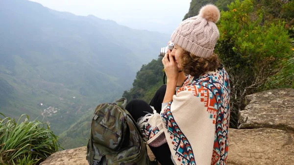Mujer joven viajero con mochila tomando fotos con cámara en la cima de la montaña —  Fotos de Stock