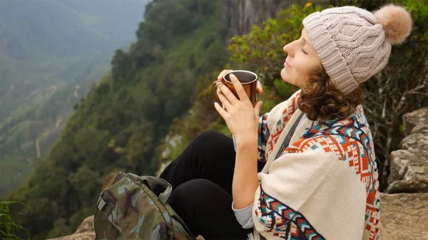 Joven viajera bebiendo té caliente después de caminar en el pico del acantilado —  Fotos de Stock