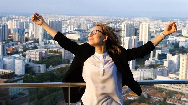 Jeune femme d'affaires avec les bras levés sur le toit de gratte-ciel en ville — Photo