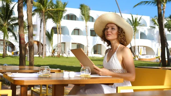 Beautiful Young Woman In Hat Reading Menu In Beach Restaurant