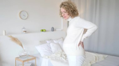 Hamilelik sırasında sorunlar ve rahatsızlık. Sırt ağrısı çeken hamile bir kadın sırtına dokunuyor..