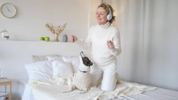 Беременная женщина танцует и играет с собакой дома — стоковое фото