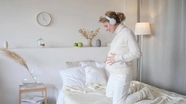 Feliz sorrindo mulher grávida em casa dançando na cama — Fotografia de Stock