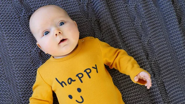 Närbild av baby porträtt med blå ögon bär glad T-shirt. — Stockfoto