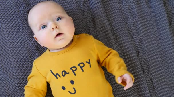 Fechar o retrato do bebê com olhos azuis vestindo camiseta feliz . — Vídeo de Stock