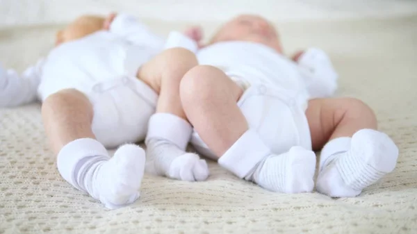 Närbild av nyfödda barn fötter tvillingar i strumpor. — Stockfoto