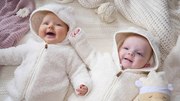 Sonrientes gemelos alegres bebés acostados en manta de punto . —  Fotos de Stock