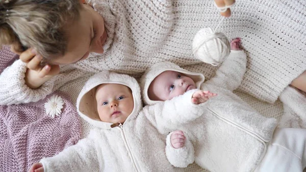 Matka v pletený svetr hrát s ní dvojče děti — Stock fotografie