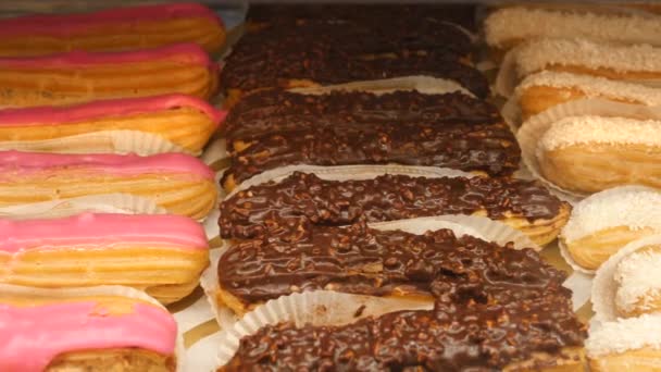 Čokoláda, jahoda a vanilka Glazované Eclairs na displeji. Closeup. — Stock video