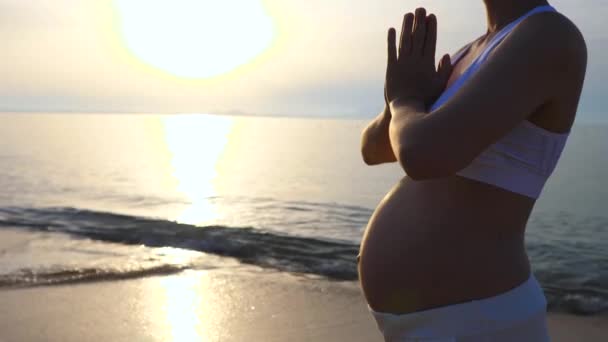 Zwangere vrouw doet yoga en meditatie bij zonsondergang aan zee — Stockvideo