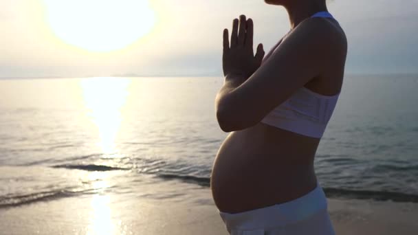 Νεαρή έγκυος γυναίκα κάνει γιόγκα στην παραλία με τα χέρια σε Namaste αίσθημα ευγνωμοσύνης. — Αρχείο Βίντεο