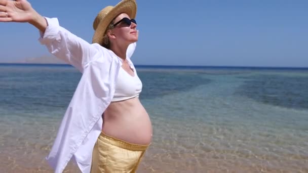 Gravid kvinna på stranden med utsträckta armar. — Stockvideo