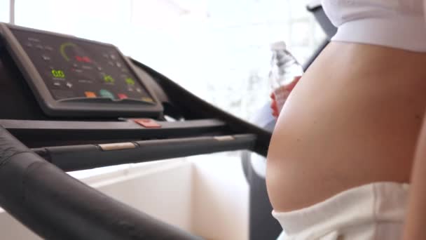 Zwangere vrouw in fitnessruimte aan het wandelen op loopband — Stockvideo