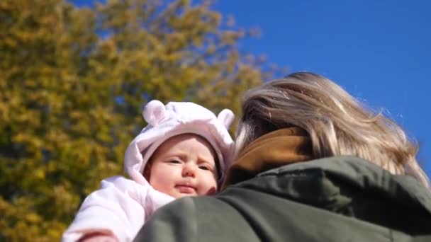 Młoda matka przytula swoje dziecko w dłoniach na zewnątrz w parku — Wideo stockowe