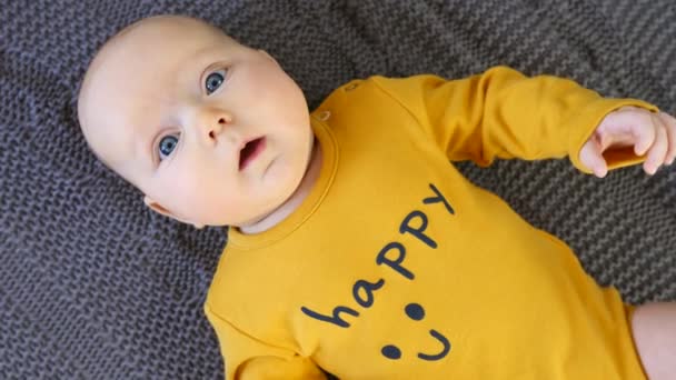 Vista superior do bebê bonito feliz que jaz no cobertor de malha cinza . — Vídeo de Stock
