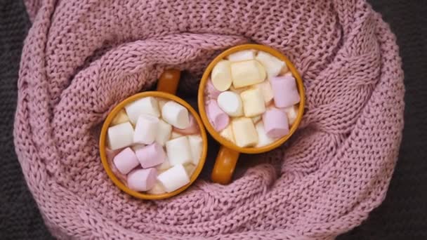 Heiße Schokolade mit Marshmallow in zwei Tassen in rosa Strickkariert gewickelt. — Stockvideo