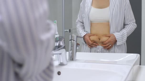 Mulher tocando barriga pós-gravidez no banheiro . — Vídeo de Stock