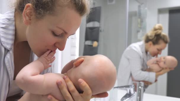 Giovane madre felice baciare il suo bambino in bagno guardando lo specchio . — Video Stock