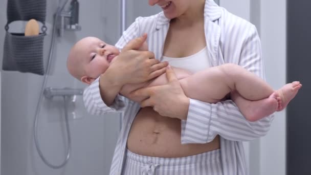Молодая мать с послеродовым животом, держащая своего ребенка . — стоковое видео