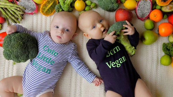 Bebés gemelos veganos comiendo brócoli . — Foto de Stock